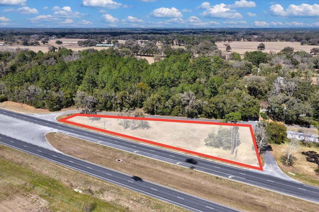 An aerial view shows a triangular, undeveloped plot of land bordered by a paved road — 18450 NE 40TH STREET, WILLISTON, FL
