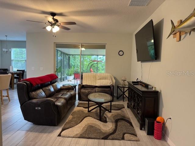 A living room features a brown leather sofa, a patterned rug, and a wall-mounted television — 3200 WINGED FOOT ROAD, MOUNT DORA, FL