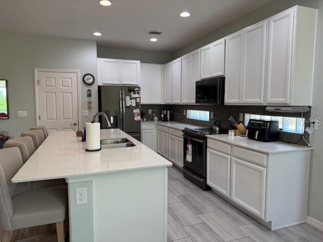 A kitchen features white cabinets, a large island with seating, and stainless steel appliances — 3200 WINGED FOOT ROAD, MOUNT DORA, FL