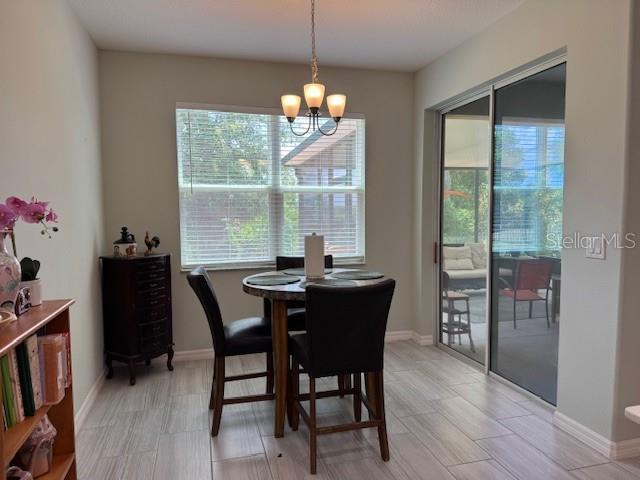 A dining area features a round table, four chairs, a chandelier, and sliding glass doors — 3200 WINGED FOOT ROAD, MOUNT DORA, FL