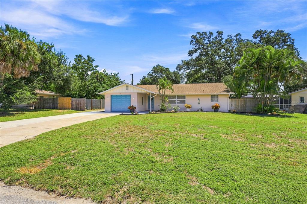 A single-story house with a light-colored exterior, a blue garage door, and a grassy yard — 411 PLANTATION ROAD, VENICE, FL