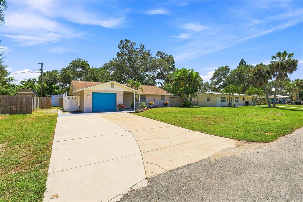 A single-story house with a blue garage door and a concrete driveway under a blue sky — 411 PLANTATION ROAD, VENICE, FL