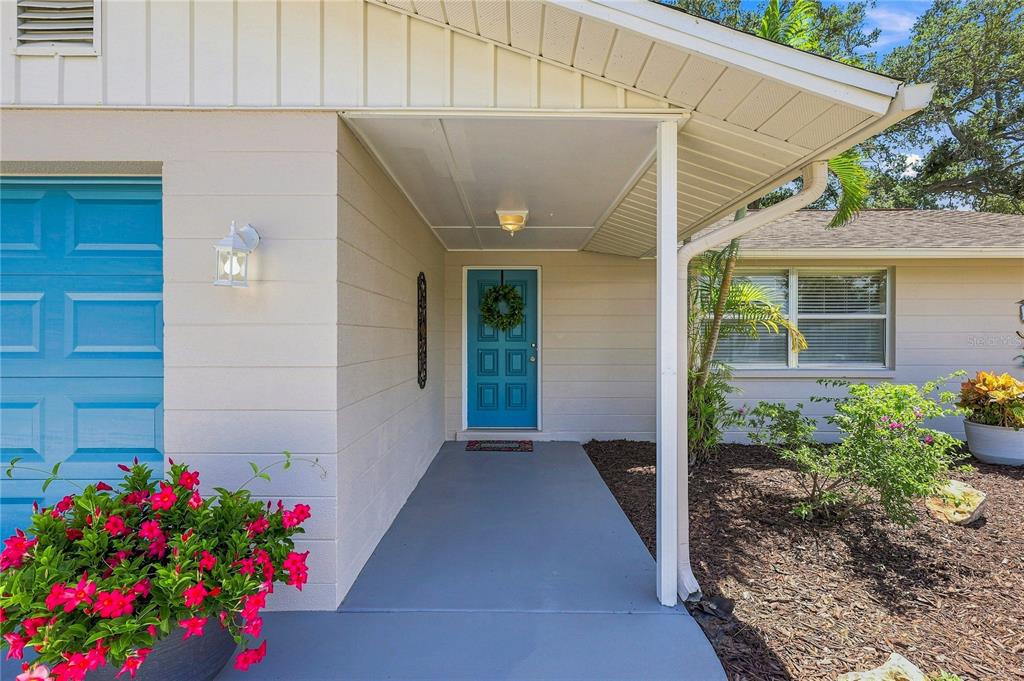 A covered entryway features a blue front door, a concrete porch, and a potted plant — 411 PLANTATION ROAD, VENICE, FL