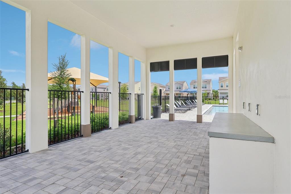 A covered outdoor patio features paver flooring, a built-in counter, and views of a pool area — 1807 LATTICE WAY, ST CLOUD, FL