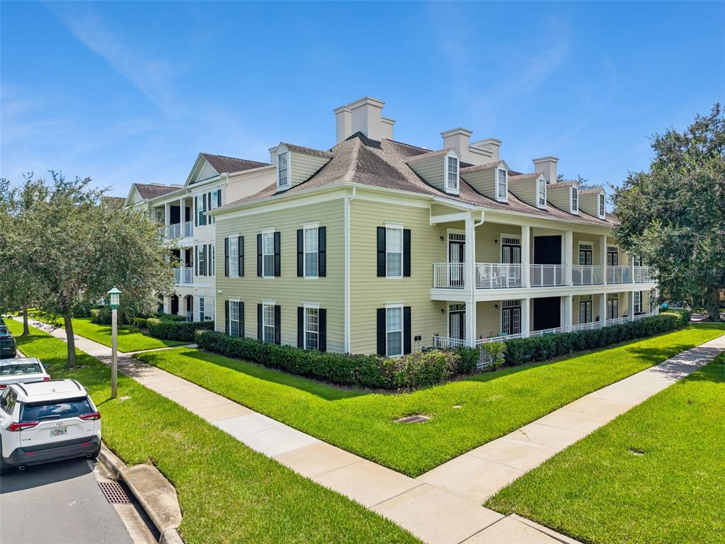 A three-story, light green apartment building with white trim and balconies under a blue sky — 239 LONGVIEW AVENUE UNIT 311, CELEBRATION, FL