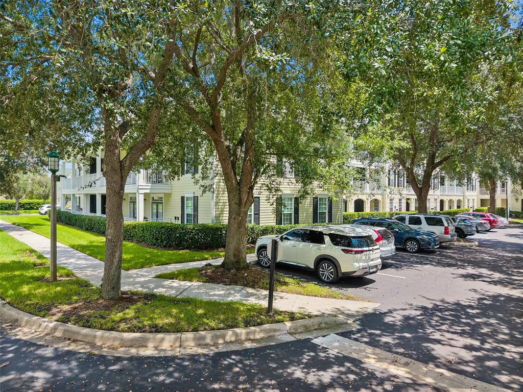 A multi-story apartment building with light yellow siding sits behind a parking lot and trees — 239 LONGVIEW AVENUE UNIT 311, CELEBRATION, FL