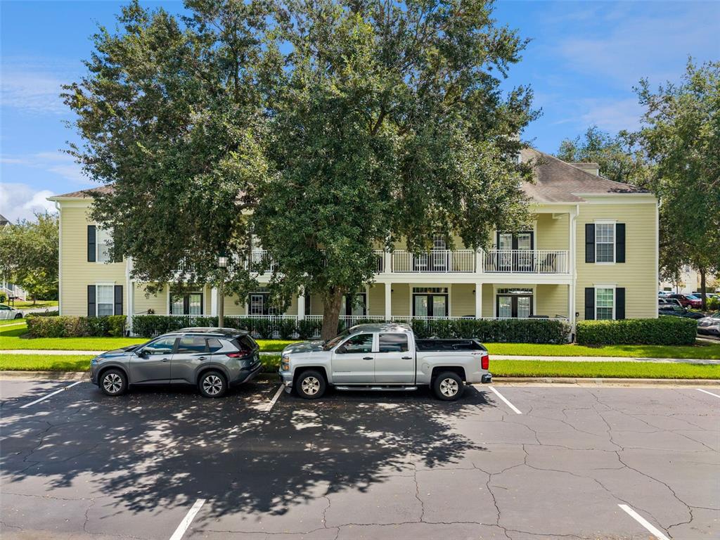 A two-story apartment building with yellow siding and a large tree in the parking lot — 239 LONGVIEW AVENUE UNIT 311, CELEBRATION, FL