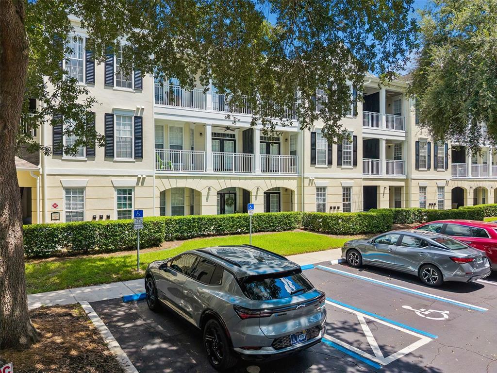A three-story apartment building with balconies and a parking lot featuring accessible spaces — 239 LONGVIEW AVENUE UNIT 311, CELEBRATION, FL