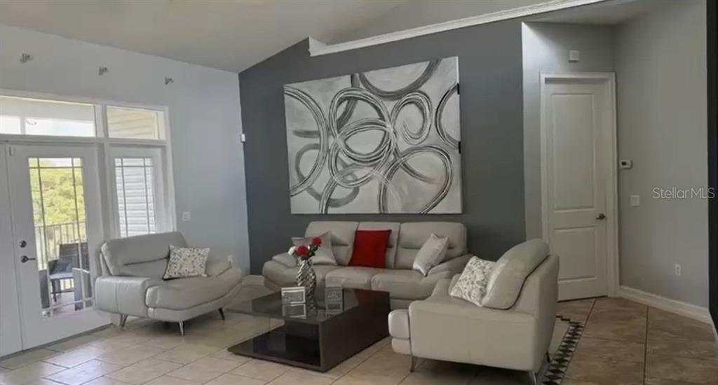 A living room features light tile flooring, a gray accent wall, and white leather furniture — 24920 SE HIGHWAY 450, UMATILLA, FL