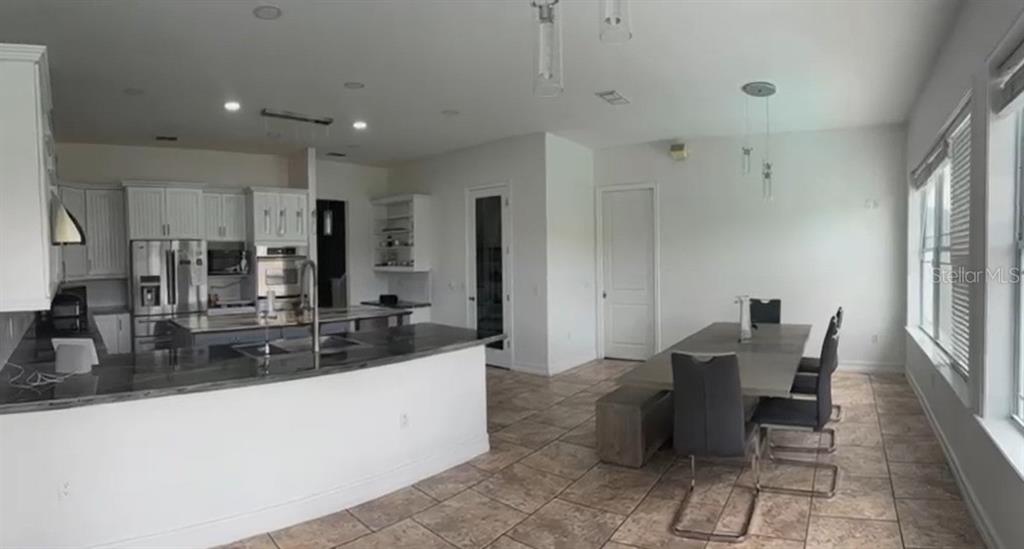 A kitchen with white cabinets and a dining area with a table and chairs — 24920 SE HIGHWAY 450, UMATILLA, FL