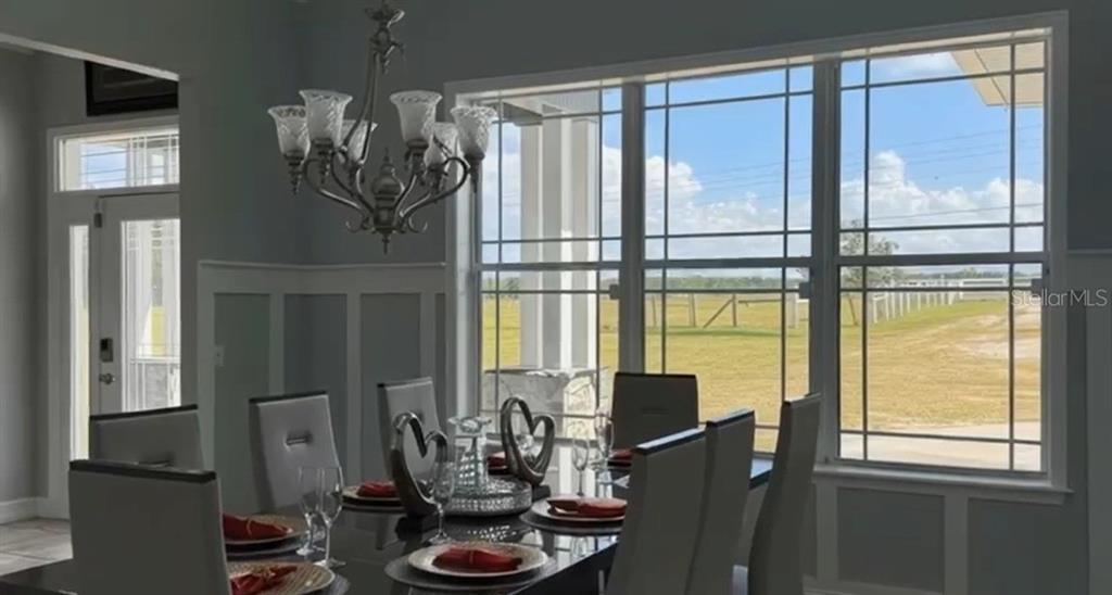 A dining room features a chandelier, a dark table with place settings, and large windows — 24920 SE HIGHWAY 450, UMATILLA, FL
