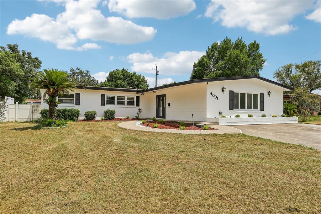 A white, single-story ranch-style house features a flat roof, dark shutters, and a palm tree — 4001 TIMBER TRL, ORLANDO, FL