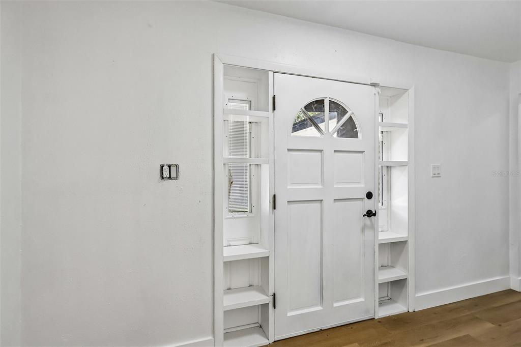 A white front door is framed by built-in shelving and side windows in a room — 4001 TIMBER TRL, ORLANDO, FL