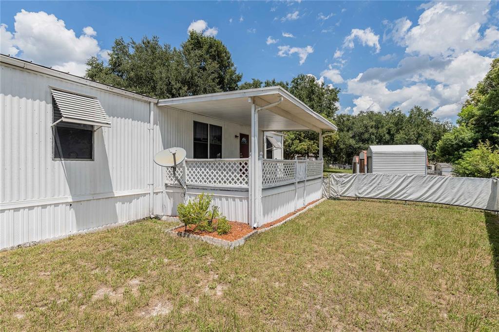 A mobile home with a white metal exterior, a covered porch, and a fenced yard — 8913 JERICHO COURT, POLK CITY, FL