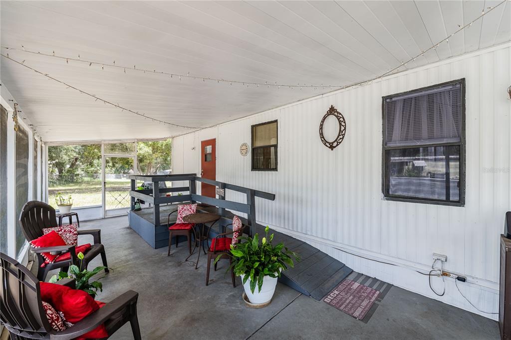 A covered porch features a wheelchair ramp, outdoor seating, and white siding — 8913 JERICHO COURT, POLK CITY, FL