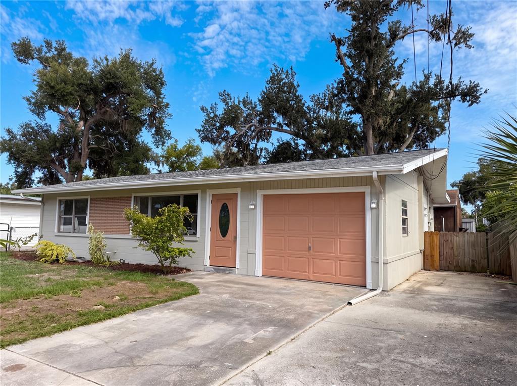 A single-story house with a light-colored exterior, a peach-colored garage door, and a matching front door — 1516 2ND AVENUE E, BRADENTON, FL