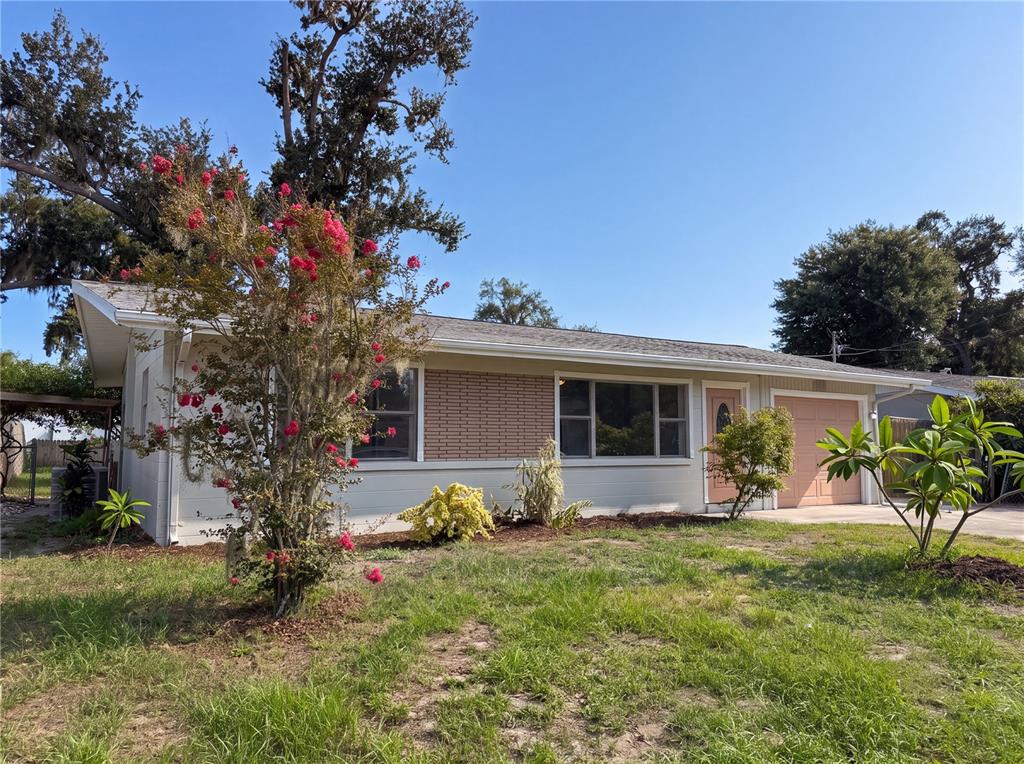 A single-story house with a brick facade, a garage, and a flowering tree in front — 1516 2ND AVENUE E, BRADENTON, FL
