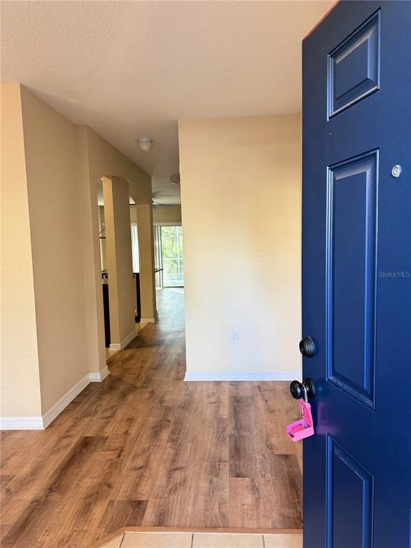 A view from an open blue front door into a home with wood-look flooring — 15802 STABLE RUN DRIVE, SPRING HILL, FL