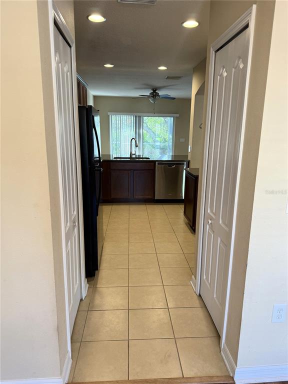 A view through a doorway into a kitchen with tile floors and dark wood cabinets — 15802 STABLE RUN DRIVE, SPRING HILL, FL