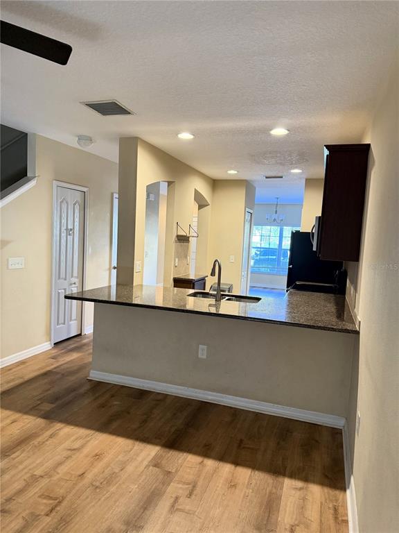 A kitchen features a granite-topped breakfast bar, dark cabinets, and wood-look flooring — 15802 STABLE RUN DRIVE, SPRING HILL, FL