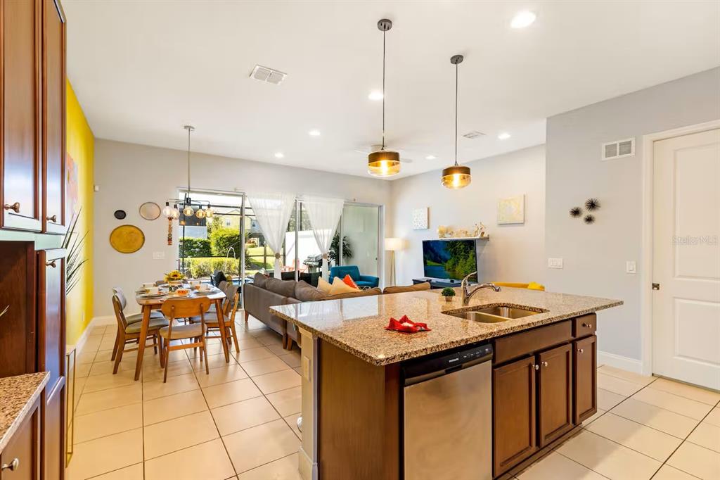 An open-concept kitchen and living area features a granite island, dining table, and tile flooring — 313 CAPTIVA DRIVE, DAVENPORT, FL