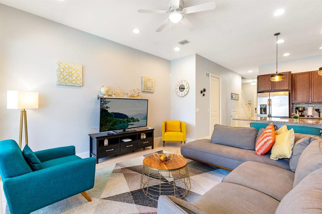 A living room features a grey sectional sofa, a teal armchair, and a television console — 313 CAPTIVA DRIVE, DAVENPORT, FL