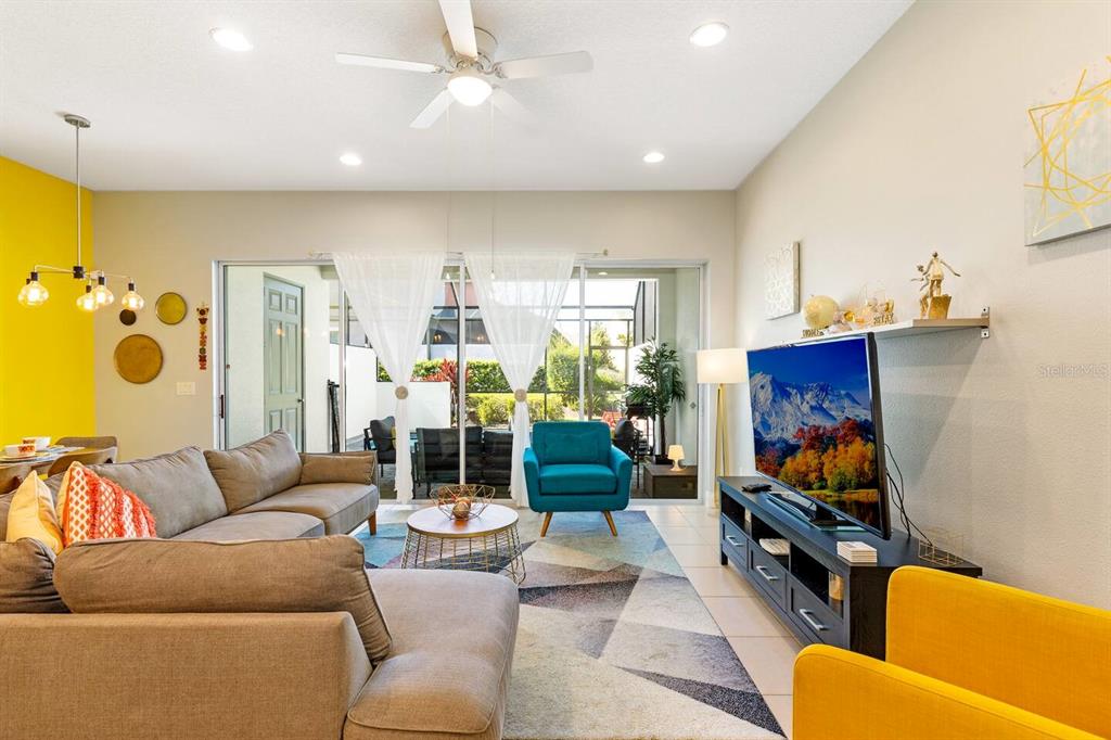A living room features a sectional sofa, a teal armchair, a television, and a sliding door — 313 CAPTIVA DRIVE, DAVENPORT, FL