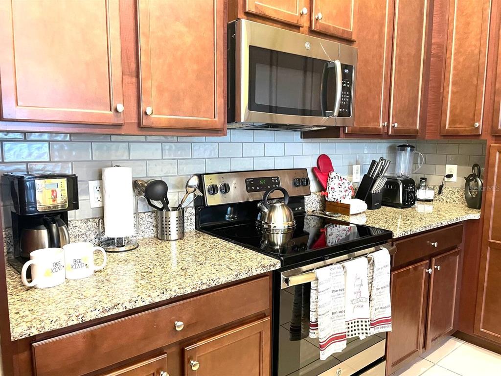 A kitchen features dark wood cabinets, granite countertops, a stainless steel microwave, and a stove — 313 CAPTIVA DRIVE, DAVENPORT, FL
