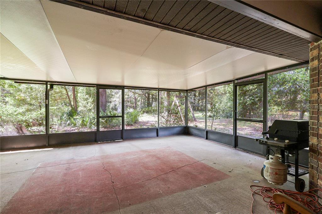 A screened-in porch with a concrete floor, a ceiling fan, and a gas grill — 144 SW ENCHANTED COURT, LAKE CITY, FL