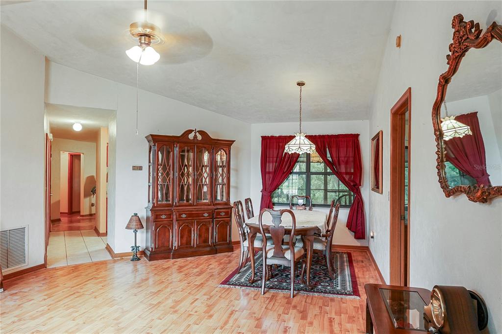 A dining room features a wooden hutch, a table with chairs, and hardwood flooring — 144 SW ENCHANTED COURT, LAKE CITY, FL