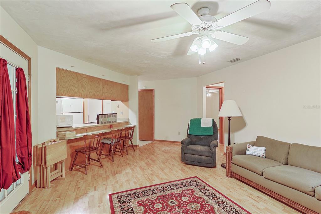 A living room with light wood flooring, a breakfast bar, and a ceiling fan — 144 SW ENCHANTED COURT, LAKE CITY, FL
