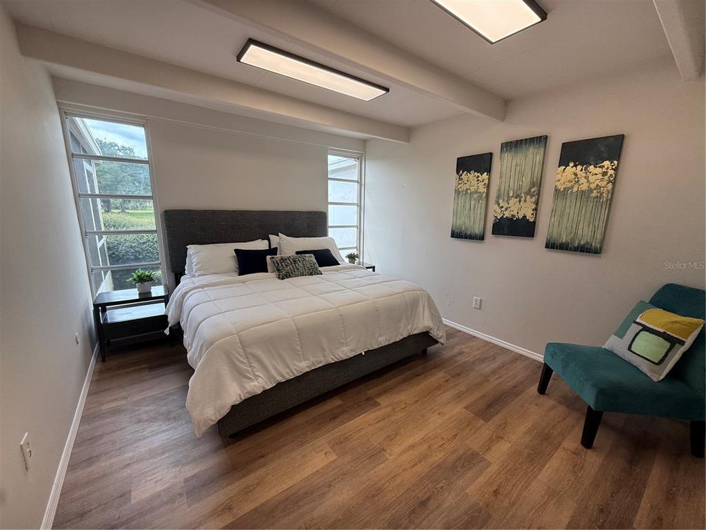An empty living room features wood-look flooring, exposed ceiling beams, and a sliding glass door — 3421 CLUB CIRCLE, LAKESHORE, FL