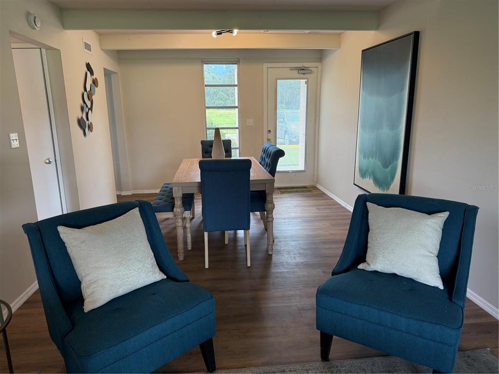 An open living area features wood-look flooring, exposed ceiling beams, and a sliding glass door — 3421 CLUB CIRCLE, LAKESHORE, FL