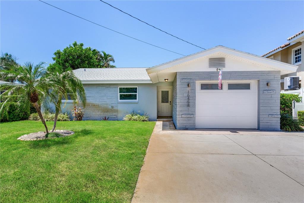 A single-story house with a gray brick facade, a front-facing garage, and a palm tree — 16458 REDINGTON DRIVE, REDINGTON BEACH, FL