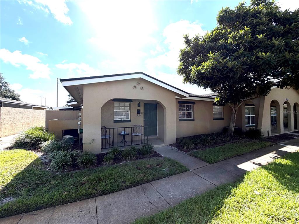 A tan, single-story residential building with a covered front porch and a large shade tree — 533 CASCADE CIRCLE UNIT 103, CASSELBERRY, FL