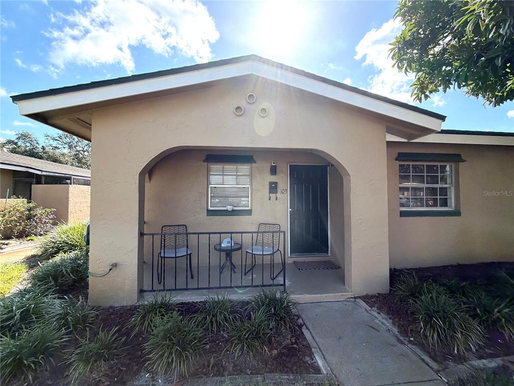A tan stucco house features a covered front porch with a black metal railing — 533 CASCADE CIRCLE UNIT 103, CASSELBERRY, FL