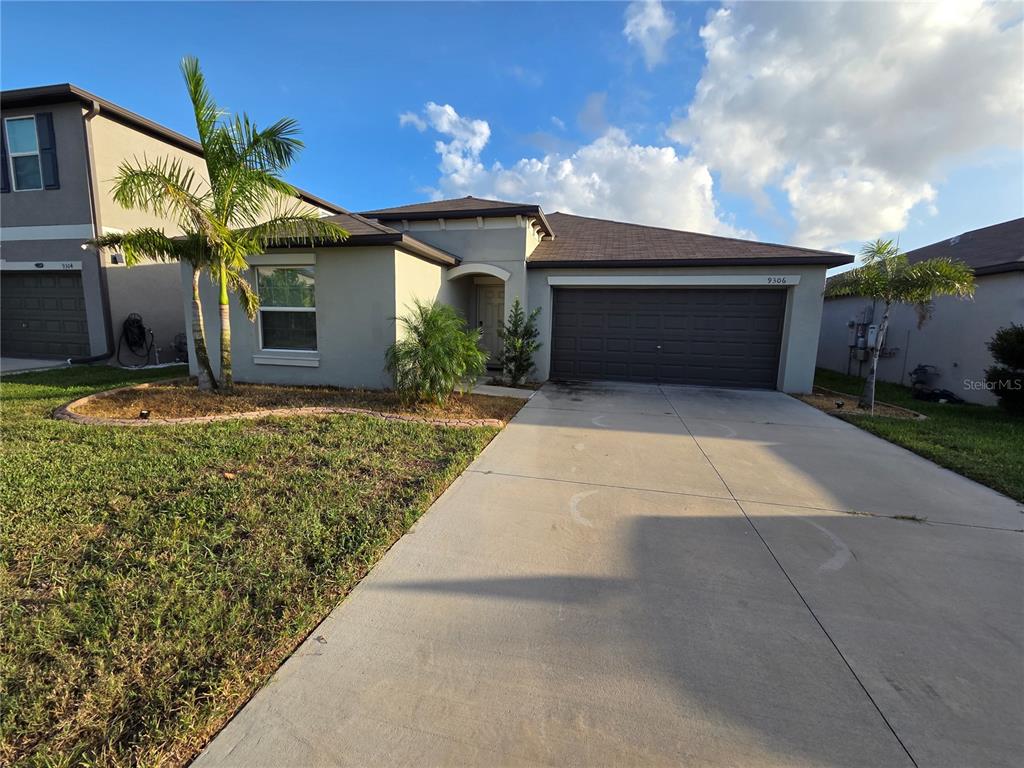 A single-story house with a gray stucco exterior, a two-car garage, and a palm tree — 9306 CHANNING HILL DRIVE, RUSKIN, FL