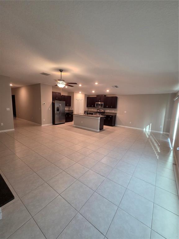An open-concept kitchen with dark cabinets and a central island overlooks a tiled living area — 9306 CHANNING HILL DRIVE, RUSKIN, FL