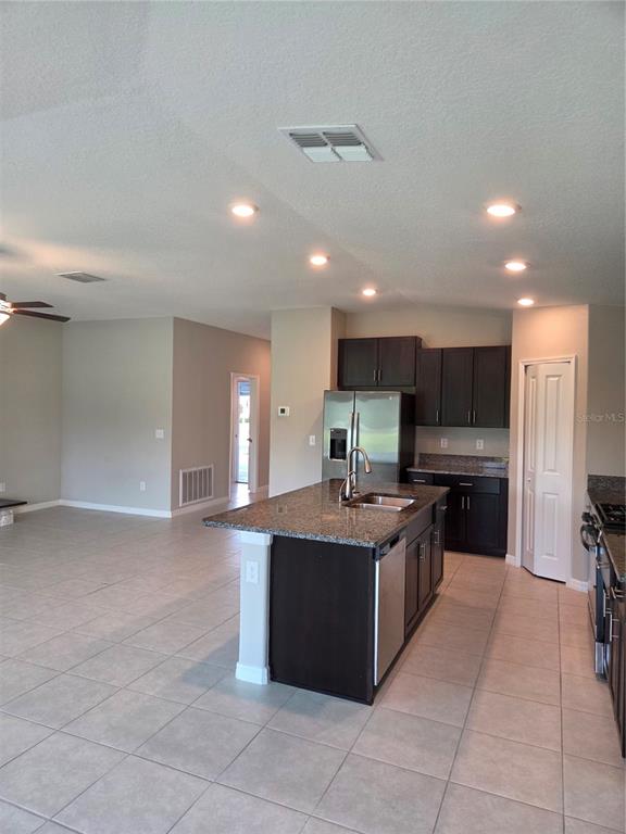 A kitchen with dark cabinets and a granite island overlooks an open living area — 9306 CHANNING HILL DRIVE, RUSKIN, FL
