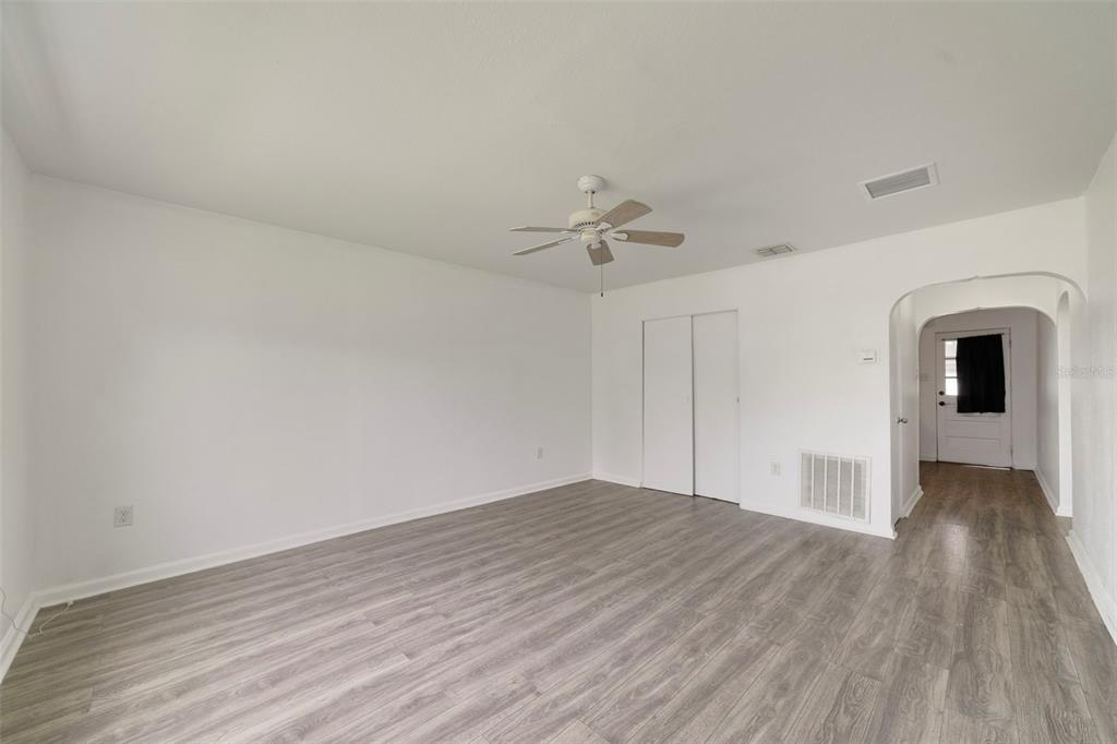 A bright, empty room features light gray wood-look flooring, white walls, and a ceiling fan — 524 & 526 SUMNER STREET, KISSIMMEE, FL