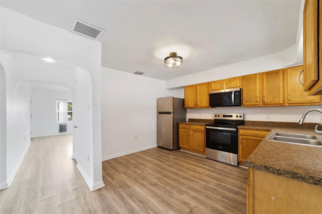 A kitchen with wood cabinets, stainless steel appliances, and wood-look flooring — 524 & 526 SUMNER STREET, KISSIMMEE, FL