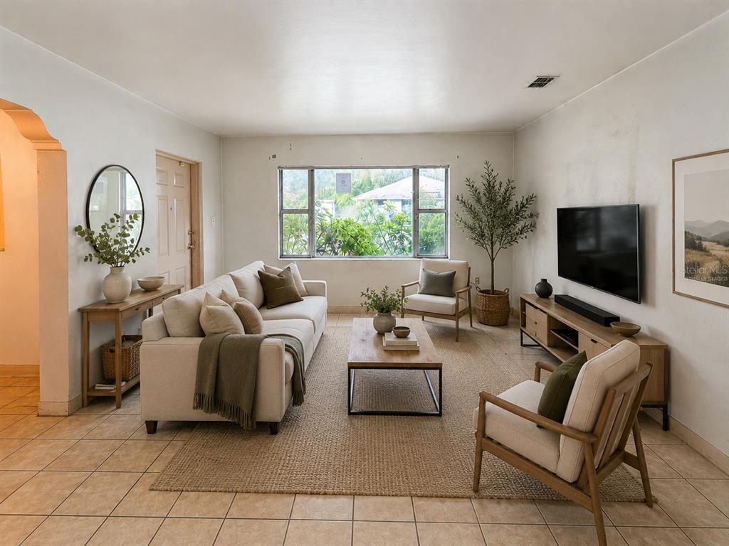 A living room with tile floors, a beige sofa, two armchairs, and a television console — 3801 E OSBORNE AVENUE, TAMPA, FL