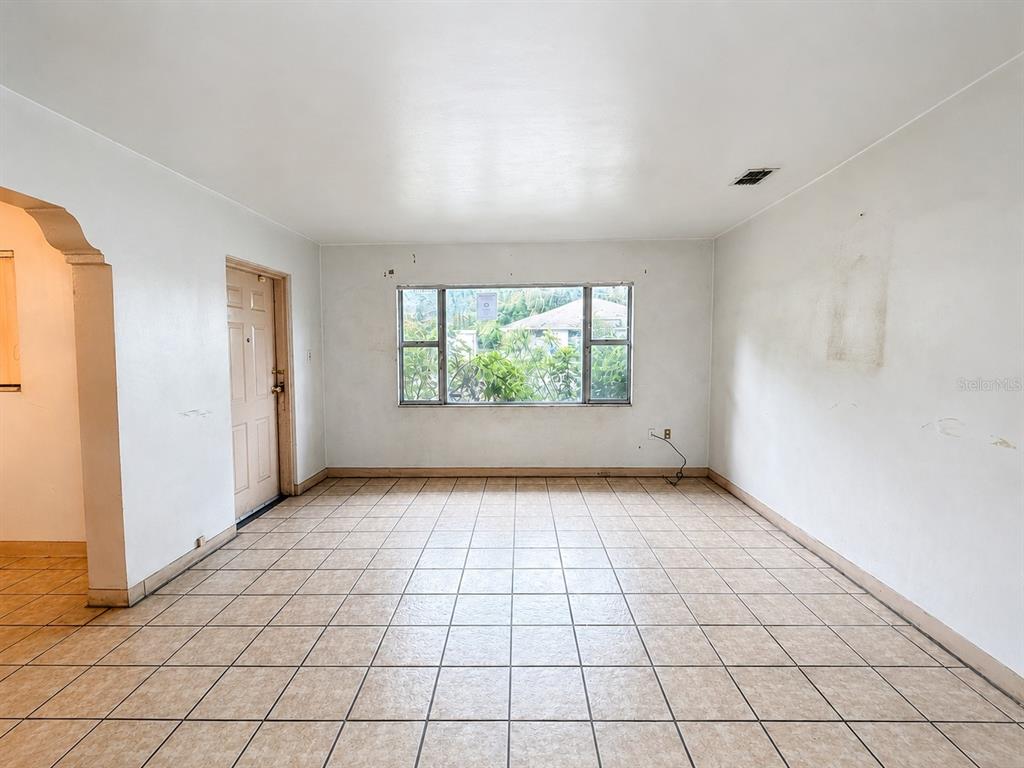 An empty room with white walls, beige tile flooring, and a large window — 3801 E OSBORNE AVENUE, TAMPA, FL