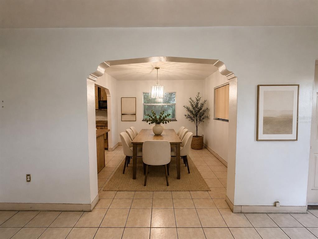 A dining room with a wooden table and chairs is viewed through an arched doorway — 3801 E OSBORNE AVENUE, TAMPA, FL