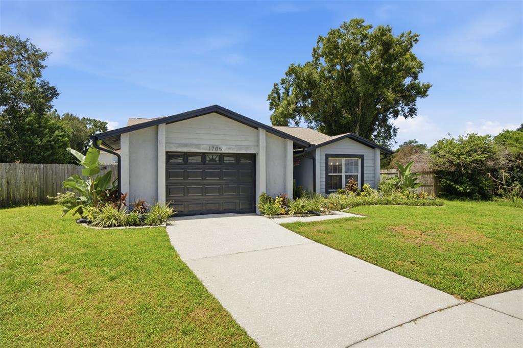 A single-story house with a gray exterior, dark garage door, and a concrete driveway — 1705 CINNABAR COURT, BRANDON, FL