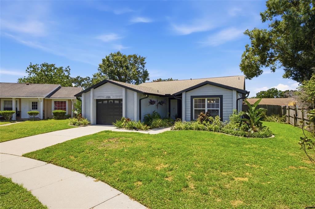 A single-story house with a gray exterior, a one-car garage, and a landscaped front lawn — 1705 CINNABAR COURT, BRANDON, FL