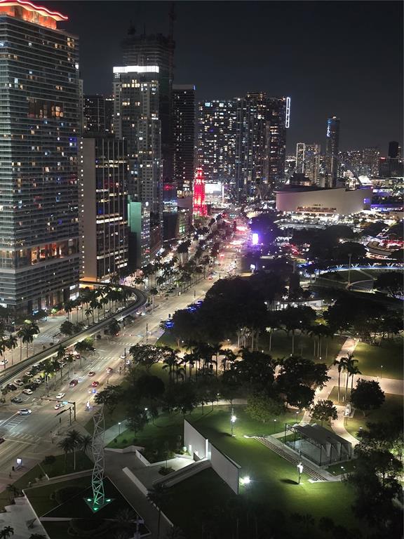 An elevated night view of a city skyline with illuminated skyscrapers, a park, and streets — 335 S BISCAYNE BOULEVARD UNIT 3400, MIAMI, FL