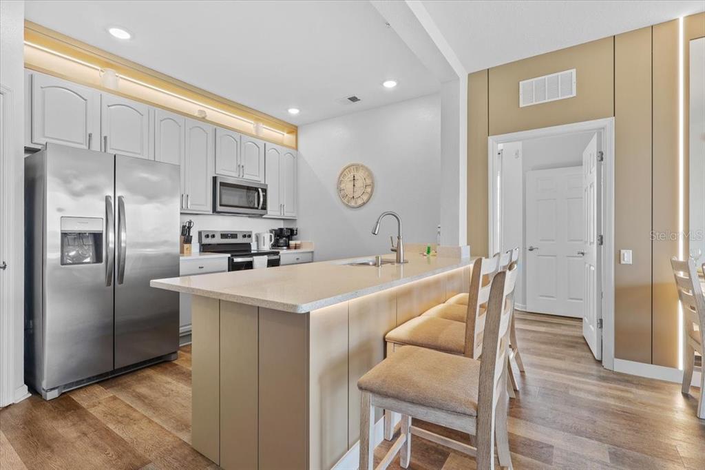 A kitchen features light-colored cabinetry, stainless steel appliances, and a central island with bar seating — 4126 BREAKVIEW DRIVE UNIT 40601, ORLANDO, FL