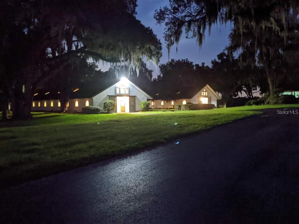 A white building with a gabled roof is illuminated at night beside a paved driveway — 5540 SE 157TH STREET ROAD UNIT (Option 1), SUMMERFIELD, FL