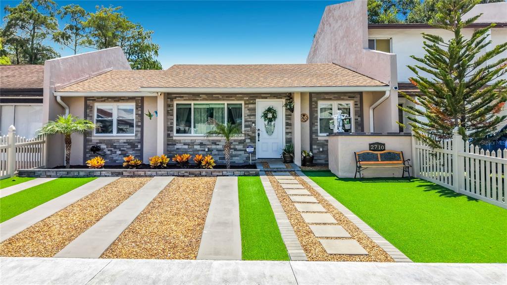 A single-story house exterior features a stone facade, a white front door, and artificial turf — 2710 CHARING CROSS WAY, ORLANDO, FL
